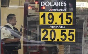 A guard stands inside a bank displaying dollar-peso exchange rates. (PHOTO: ap.org)